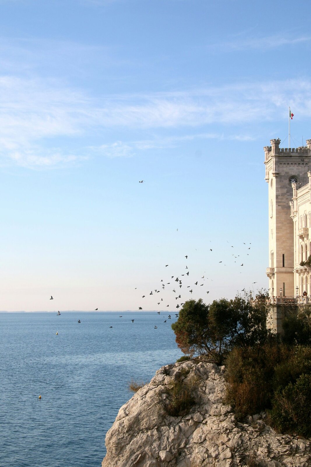 Castello di Miramare a Trieste con uccelli in volo sul mare Adriatico